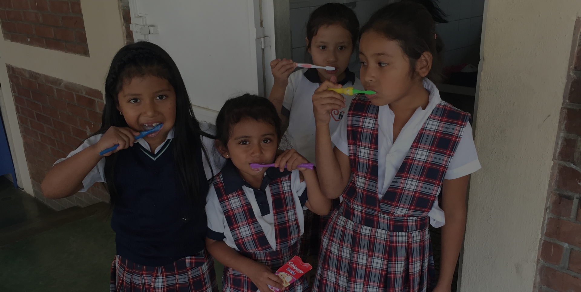 Girls in school uniform brushing their teeth together at the IMA School in Guatemala