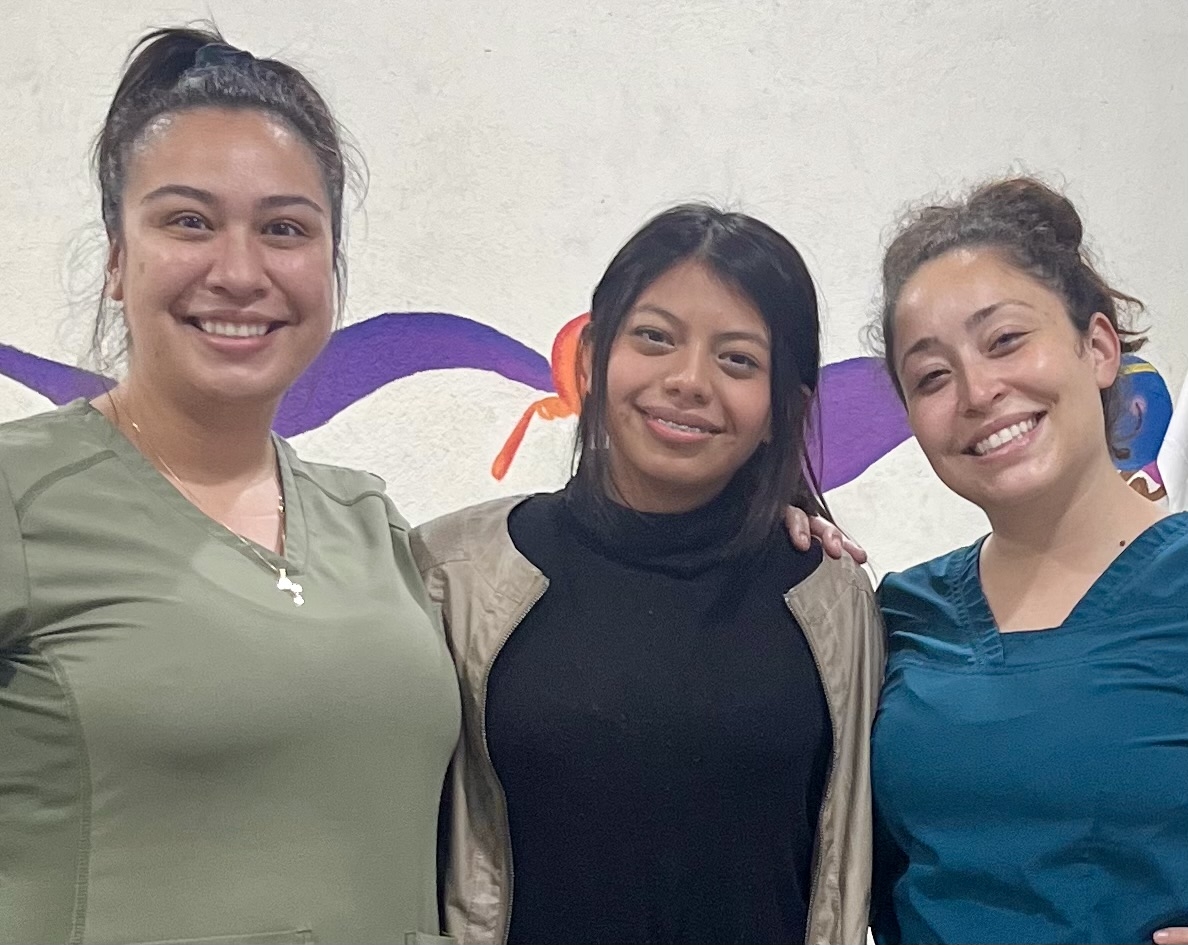 Melany, an IMA School student, standing between two United Tooth Fairies dental hygienists after her orthodontic treatment