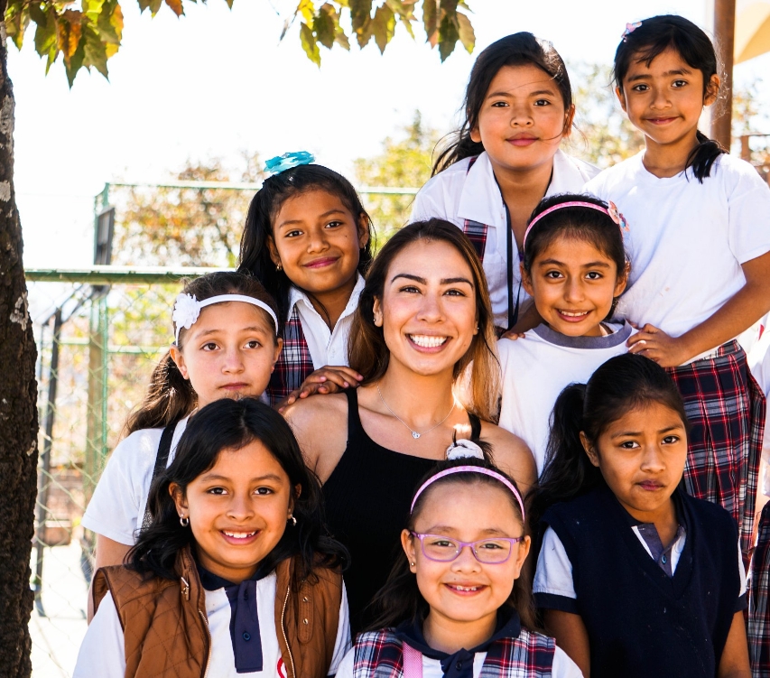 A United Tooth Fairies volunteer surrounded by smiling students from the IMA School for Girls